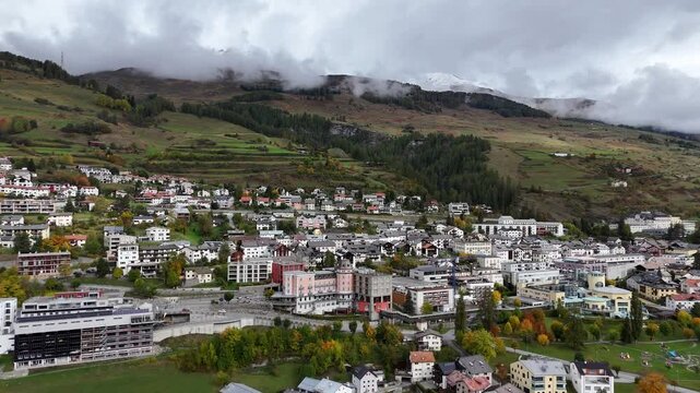 Scuol, switzerland, showing a scenic town with lush green hills and mountain backdrop, aerial view
