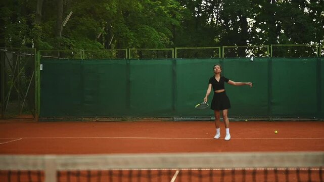A tennis player plays sports on a tennis court . The athlete trains in tennis. An African girl plays tennis. 