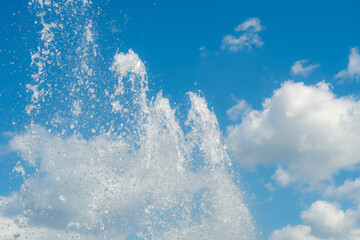 Bright jets of a fountain against a blue sky. Abstract summer, fresh background on the theme of relaxation and happiness.