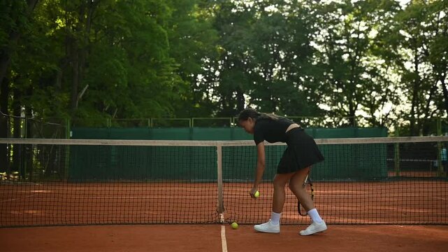A tennis player plays sports on a tennis court . The athlete trains in tennis. An African girl plays tennis. 