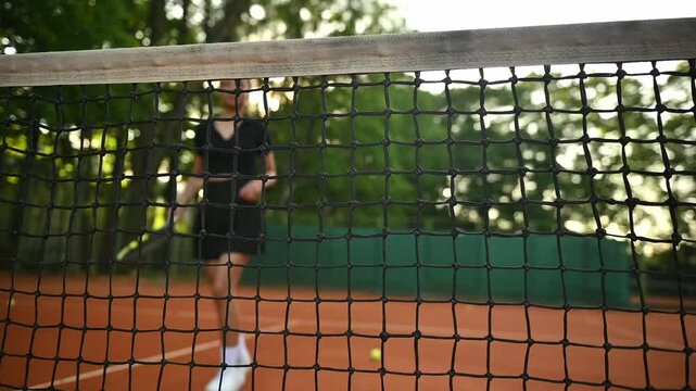 A tennis player plays sports on a tennis court . The athlete trains in tennis. An African girl plays tennis. 