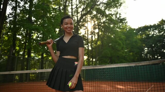 A tennis player plays sports on a tennis court . The athlete trains in tennis. An African girl plays tennis. 