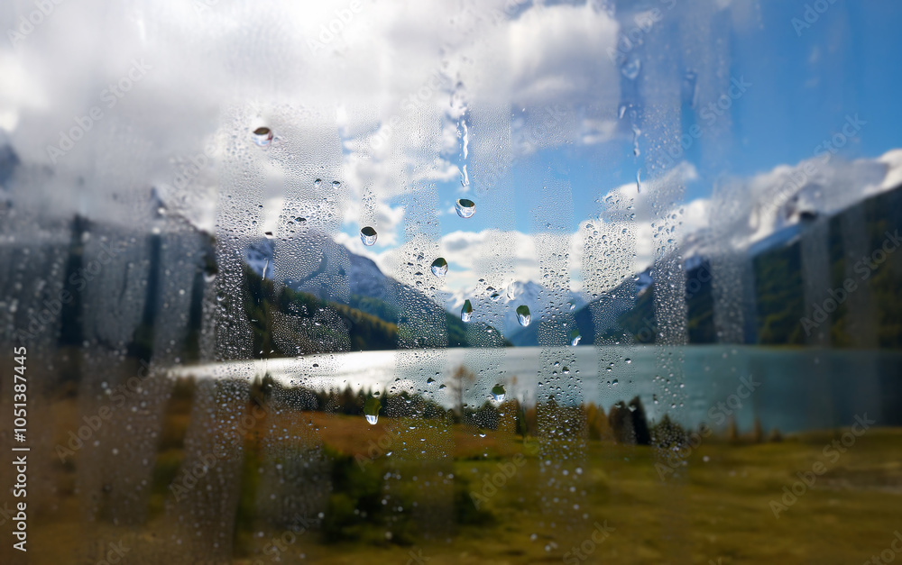 Poster A view of a lake surrounded by mountains seen through a window with raindrops.