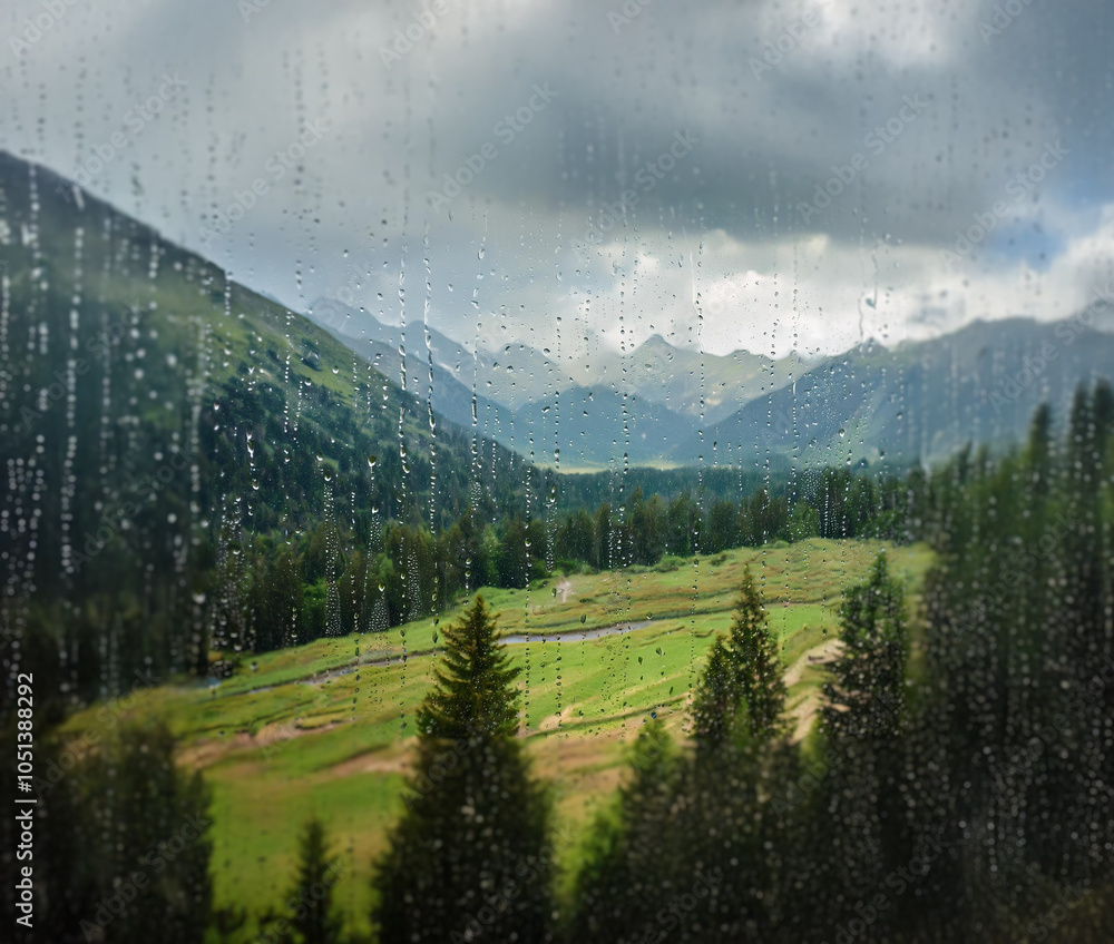 Poster A view of a mountainous valley with a river running through it seen through a rain-streaked window.