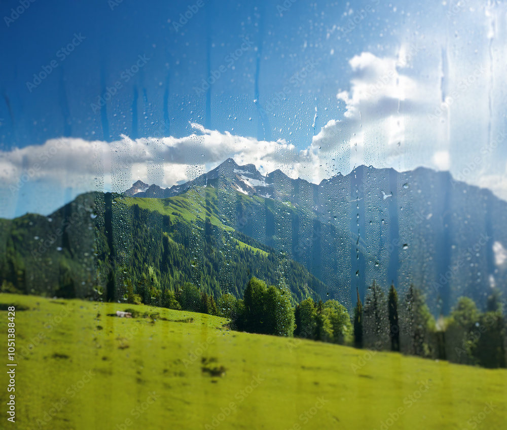 Poster A view of a mountain range through a window with rain drops.