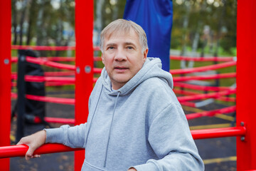 Mature man training on parallel bars on a sports ground