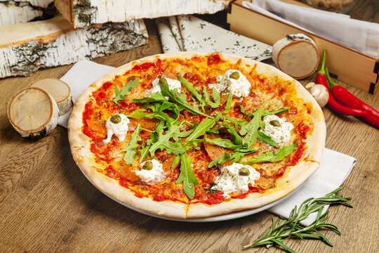 Italian pizza with salmon, cream cheese and arugula. Cafe, lunch.
