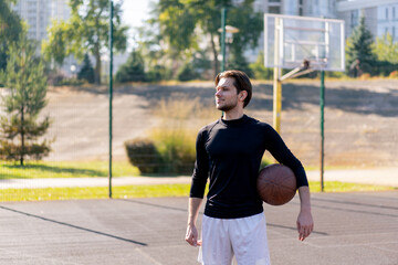 a sports ground basketball field active recreation guy in white shorts and black t-shirt stands with ball in hands posing in front of camera
