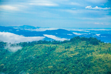 A lush green mountainous landscape with clouds and blue sky.