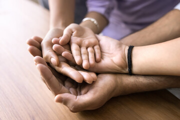 Father holding empty hands of mom and two little kids. Stack of open parents and children palms symbolizing family day, gesture of support, insurance, care, childcare. Cropped close up shot