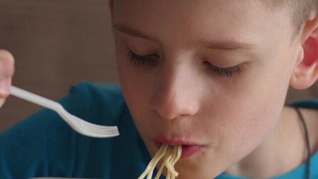 Caucasian boy 10-12 years old eats instant noodle soup, child with appetite vermicelli plastic fork
