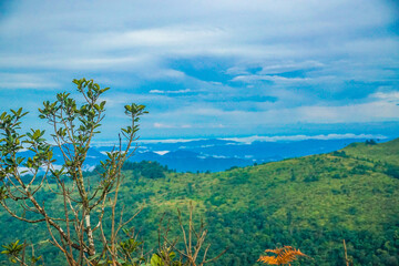 Obraz premium A breathtaking view of lush green hills under a vibrant blue sky with fluffy clouds.