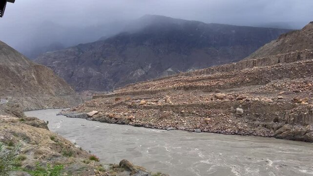 A breathtaking landscape showcasing the Kunar River meandering through Babusar Valley, with dramatic mountain ranges under a cloudy sky. Ideal for nature and travel-themed projects.