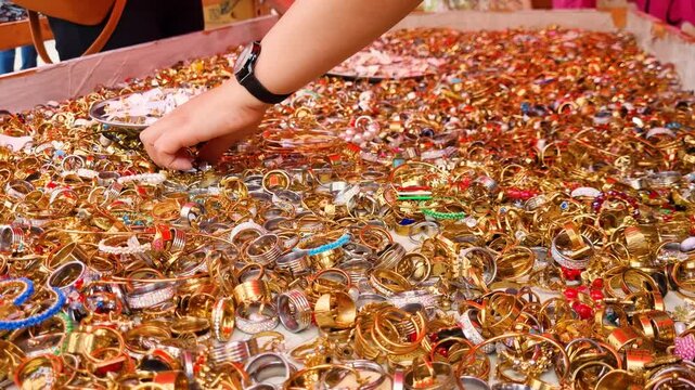 Golden and silver fingerrings on display, buyers digging through it