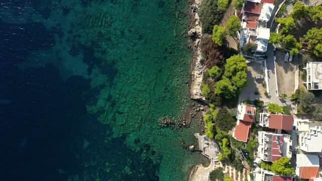High above drone flying against overhead with ocean cliffs and houses