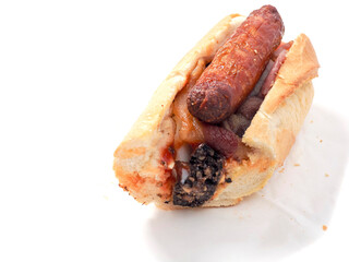 Traditional Irish breakfast roll with cooked sausages, bacon or rashers and black and white pudding in a round bread on light color paper. Popular meal with high calorie count.