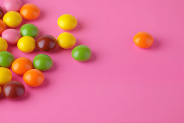 Colorful Skittles candies on a pink background