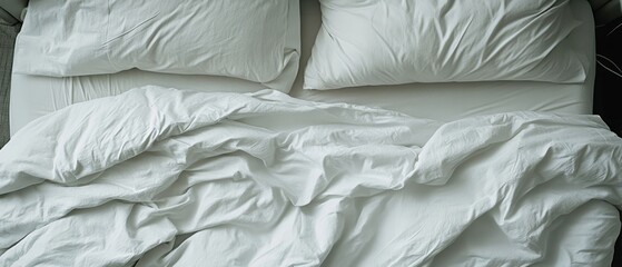 Soft white sheets and pillows create a tranquil atmosphere in the unmade bed, inviting relaxation and comfort on a calm morning