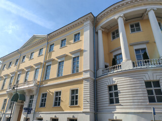 large yellow building with multiple windows and an arched doorway, showcasing classical architectural design. The structure reflects the enduring appeal of historical elegance in urban environments.