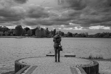 Smutna dziewczyna pogrążona w żałobie w pochmurny dzień stojąca nad brzegiem rzeki, dramatyczne zachmurzone niebo  © Paweł Kacperek