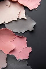 A collage of torn paper with pink, gray, and black pieces