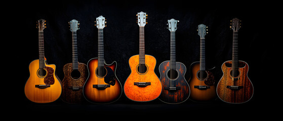 Fototapeta premium Five guitars aligned in a row against a black backdrop; each adorned with orange and brown paint