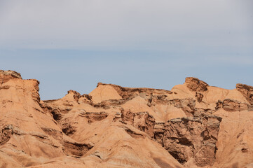 A breathtaking aerial view of a rugged desert canyon landscape at golden hour, showcasing dramatic rock formations, sandy terrain, and a winding road under a clear sky