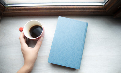 young woman drinking coffee and reading book at home