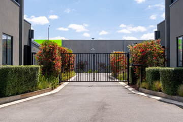 The gated community entrance features a paved access road leading to an upscale residential complex...