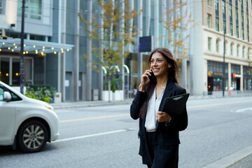 A woman is talking on her cell phone while walking down a street