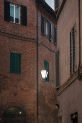An old street lamp on the wall of a brick house.
