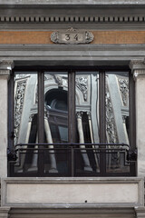 A window in a classic style, in the glass of which another window is reflected.