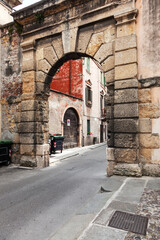 A narrow Italian street passes through a rusticated arch.