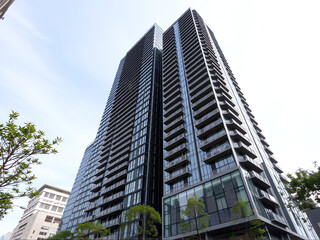 Obraz premium Modern high-rise residential building with glass façade in an urban setting on a clear day