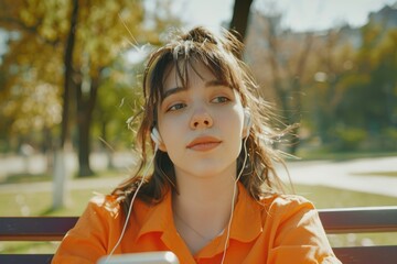 A woman sits on a park bench enjoying her favorite tunes