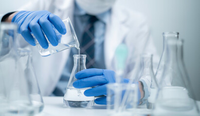 Fototapeta premium Hands holding pouring fluid liquid beaker flask test tube glassware sample laboratory for compare in medicine chemical biology medical medicine science experiment technology analysis