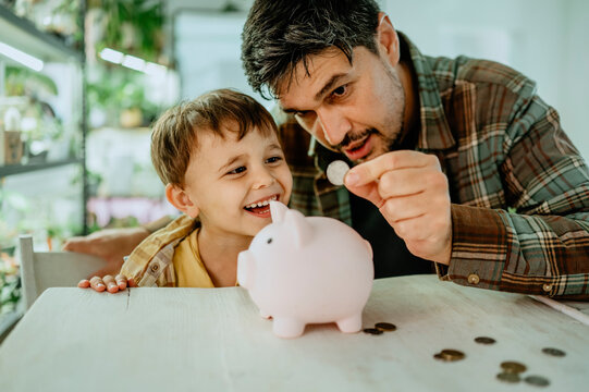 Father teaching son to save money at home