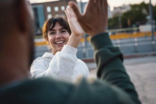 Happy couple giving high-five to each other at footpath