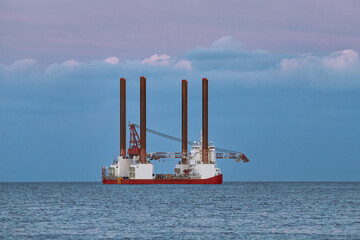 Jack up wind turbines installation vessel in the sea, with beautiful colourful sky.