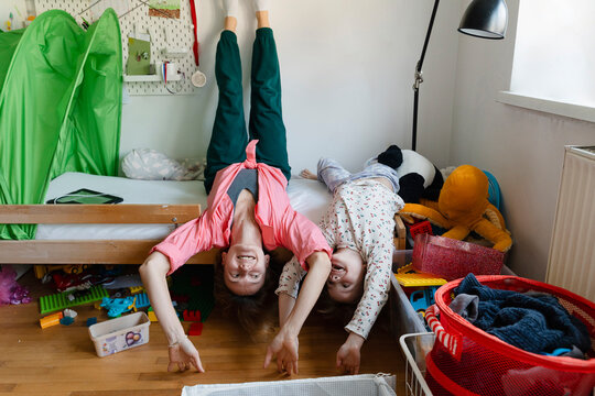 Playful mother and son sleeping upside down on bed at home