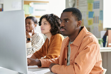 Group of colleagues, including Black person and Caucasian, collaborating on project in modern office. Focused expressions while sharing ideas and insights