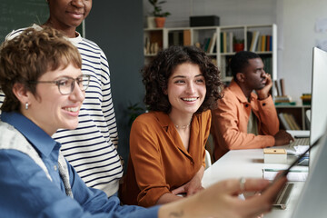 Group of multiracial colleagues collaborating on project while sitting at desk in modern office...