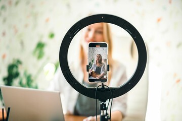 coach or influencer recording content with professional light and phone, creating a personal...