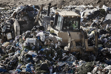 Heavy machinery shredding garbage in an open air landfill. Pollution