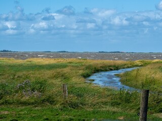 Blick über das Naturschutzgebiet Wattenmeer bei Hochwasser und stürmischer See mit einer Nordseeinsel im Hintergrund