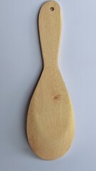 A wooden cooking spoon with a wide, flat head and a curved handle. The spoon is light brown in...