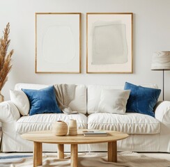 Two minimalist abstract art prints in beige tones. framed and hung above a white sofa with blue cushions in a modern living room