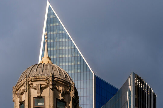 This capture focuses on a sharp-angled skyscraper that pierces a cloudy sky, highlighting modern architecture's elegance and a contrast with historic decorative buildings nearby in London UK