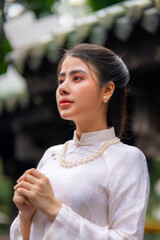 Vietnamese girl with Ao Dai dress standing in temple in Ho Chi Minh city, Vietnam. Ao dai is famous...