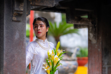 Vietnamese girl with Ao Dai dress standing in temple in Ho Chi Minh city, Vietnam. Ao dai is famous...